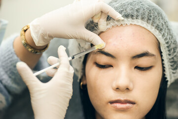 Closeup hand. Doctor injection for acne treatment on forehead. Add noise film grain. Surgery botox injection.