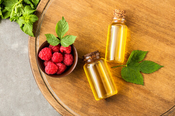 Bottles of raspberry essential oil on wooden tray