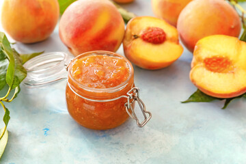Jar with tasty peach jam on table