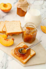 Bread with tasty peach jam on table