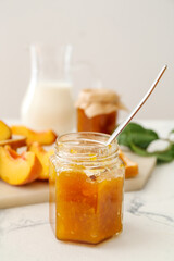 Jar with tasty peach jam on table