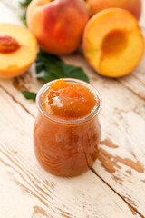 Jar with tasty peach jam on wooden table