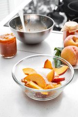 Bowl of fresh peaches with sugar on light table