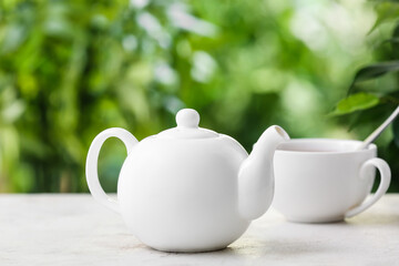 Teapot and cup of tea on table against blurred background