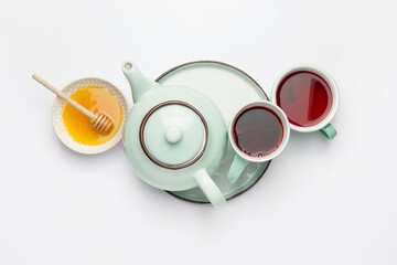 Composition with teapot, cups of tea and honey on white background