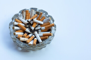 Cigarette butts in glass ashtray on white background.