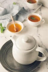 Teapot, honey and cup of tea on table