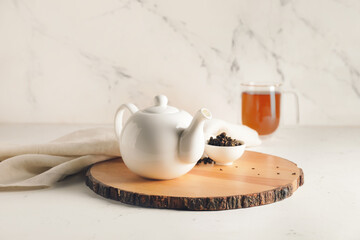 Teapot and dry tea leaves on table