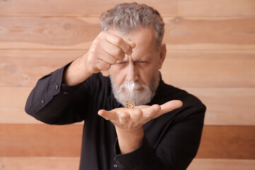 Male fortune teller with pendulum on wooden background