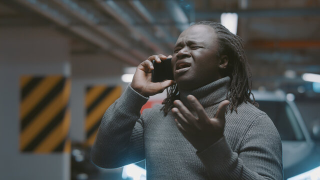 Bad news. African american black man speaking on the phone in the underground parking. High quality photo