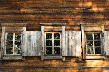 An old window with platbands on the background of a log wall.