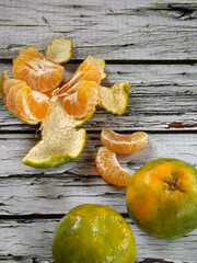 Image of the whole and peeled of jeruk keprok or Indonesian local orange fruits which commonly has green with bit yellow skin. The taste is very refreshing, sweet with bit sour. High angle picture.