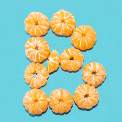 Creative layout of the letter B from peeled tangerines on a blue background. Flatlay.