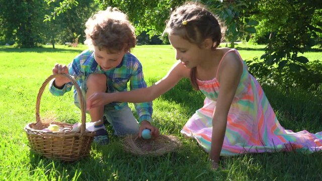 Two children boy and girl having easter egg hunt in garden backyard