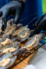 manos de chef  preparando camarones a la mantequilla partidos por la mitad y en la parrilla .

se condimentan con sal y pimienta  y se parten por mitad con cuchillo.