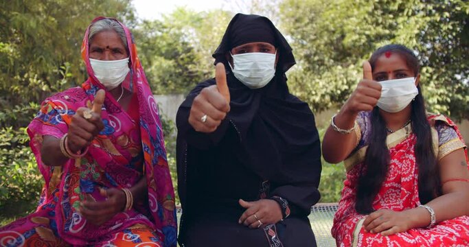 Handheld slow-motion shot of 3 women wearing face masks with Sari and Hijab raise hands to gesture sign to stop and thumbs up for best of luck wishes  protect and be aware during coronavirus covid-19 