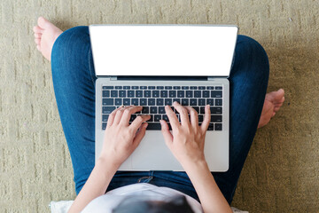 Young woman working on a laptop sitting on sofa at home