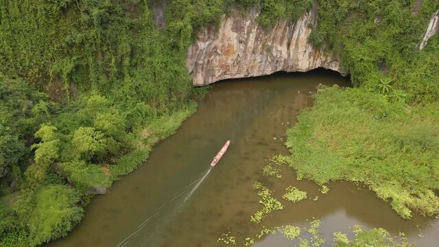 Aerial shot of beautiful limestone mountains with passes carved by a river in Ninh Binh region, a famous tourist destination in northern Vietnam. Travel to Vietnam concept. An entrance to a cave which