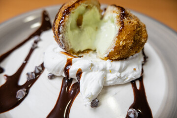 Fried ice cream with chocolate syrup and cream on plate