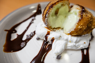 Fried ice cream with chocolate syrup and cream on plate