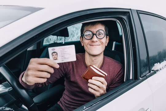 Funny nerd and geek in huge ridiculous glasses shows his drivers license. Concept of police checks on the roads and the correction of vision for drivers