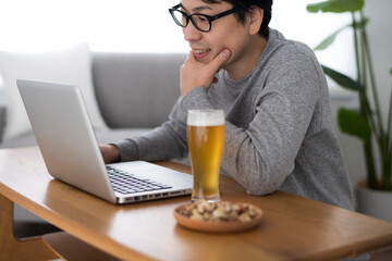 自宅でオンライン飲み会をしている男性