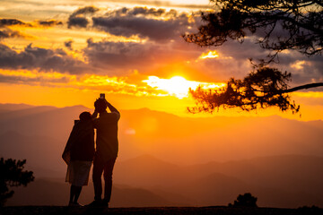 Couple photograph mountain view with sunset sky.