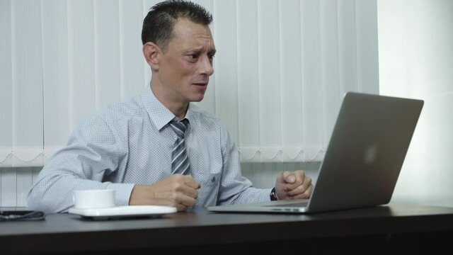 A business man who is a company employee using a laptop to work in an office Is feeling frustrated, stressed, angry, and pissed off at his job.