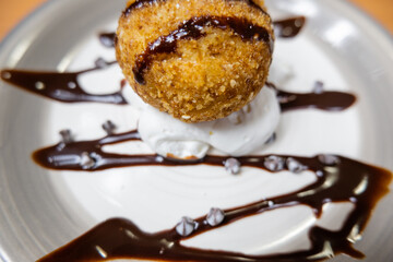 Fried ice cream with chocolate syrup and cream on plate