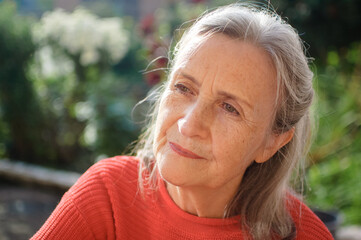 Beautiful old grandmother with grey hair and face with wrinkles outdoors relaxing at park during sunny day