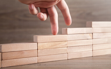 Fingers climbing the stairs made with wooden blocks.