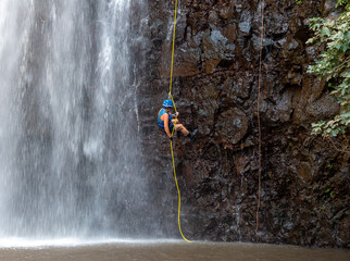 An athlete doing rock climbing - snapping - descends down a waterfall  from a mountain near the...