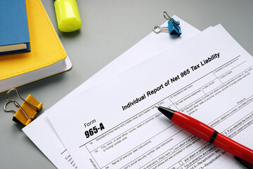 Business concept about Form 965-A Individual Report of Net 965 Tax Liability with sign on the sheet.
