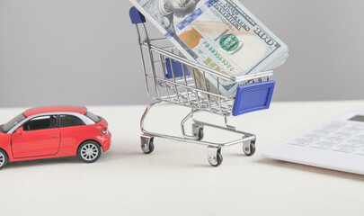 Red toy car and money in shopping cart. Buy car