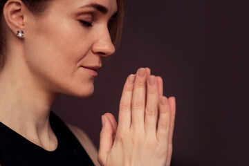 middle aged woman meditating with her eyes closed, practicing Yoga with hands in prayer position.