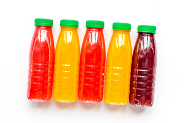 plastic bottles with fruit drinks on white background top view