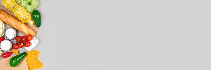 Banner. Flat lay composition - food donations on gray background with copyspace - pasta, fresh vegatables, canned food, baguette, cooking oil. Food donation and food bank concept