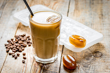 cold coffee glass with ice cubes on wooden table background