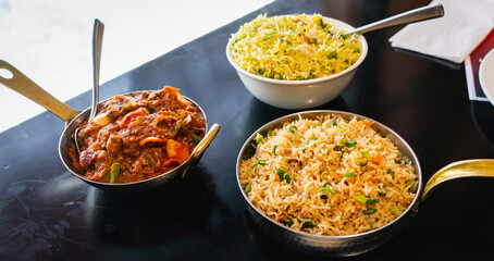 Selective focus of Vegetable Fried Rice, Kadai Mushroom, and Peas Pulao served on a black table.