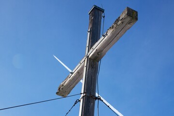 Fototapeta na wymiar Gipfelkreuz vor blauem Himmel und Flugzeug