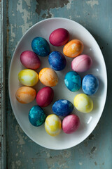 Easter eggs in white dish on light blue old concrete background