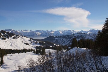 Fototapeta na wymiar Winterlandschaft der schneebedeckten bayerischen Alpen über Wolken vor blauem Himmel