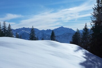 Fototapeta na wymiar Winterliche Landschaft der schneebedeckten bayerischen Alpen vor blauem Himmel im Sonnelicht