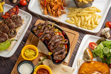 Meat fajita, meatballs, chicken schnitzel and chicken with curry sauce on wooden table.