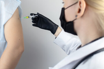 Infectious disease doctor gives the patient a medical vaccination in the shoulder. Immunization...