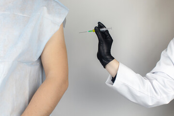 Infectious disease doctor gives the patient a medical vaccination in the shoulder. Immunization against tetanus, influenza, dysentery, whooping cough, diphtheria, measles, shigellosis and hepatitis B