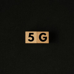 5G word on wooden cube. Flat lay view concept on black background. Square size of photo.