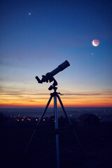 Silhouette of a astronomy telescope with twilight sky.