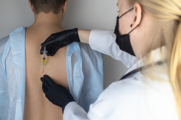 An orthopedic surgeon gives an injection in the spine. Treatment of osteoarthritis with hormonal...