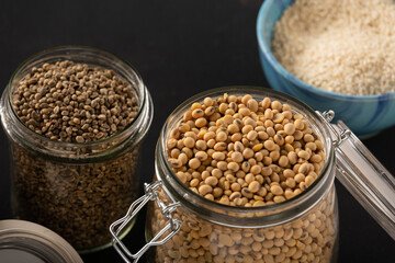 Soybeans, cannabis grains and rice in jars on a dark background